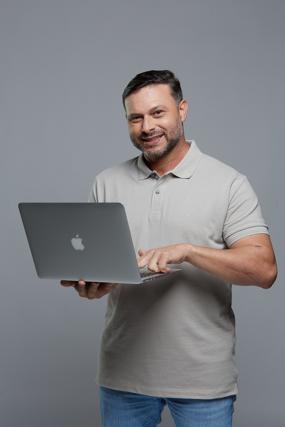 Homem segurando notebook e sorrindo para a foto